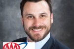 A man smiling and wearing a suit with AAA Northeast Logo in the bottom left corner